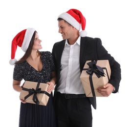 Photo of Beautiful happy couple in Santa hats holding Christmas gifts on white background