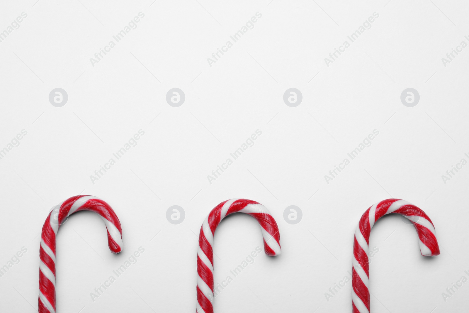 Photo of Many sweet Christmas candy canes on white background, flat lay. Space for text