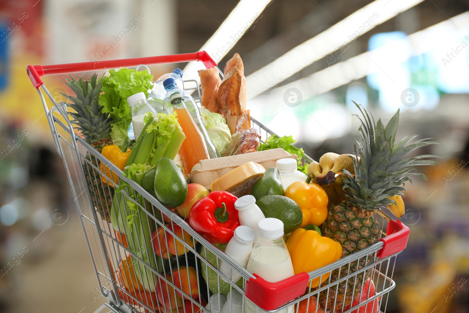 Image of Shopping cart with different groceries in supermarket