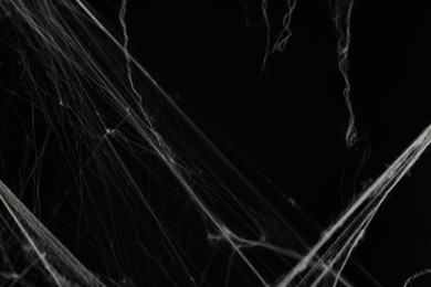 Photo of Creepy white cobweb on black background, closeup