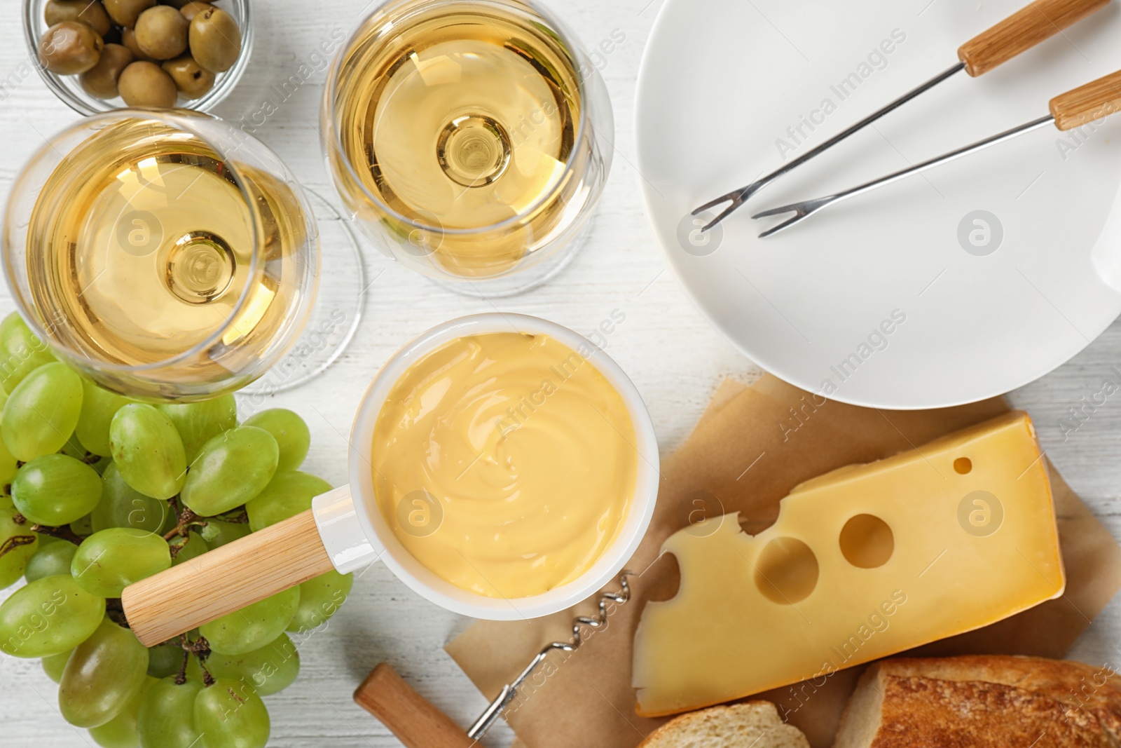 Photo of Flat lay composition with pot of tasty cheese fondue and products on white wooden table