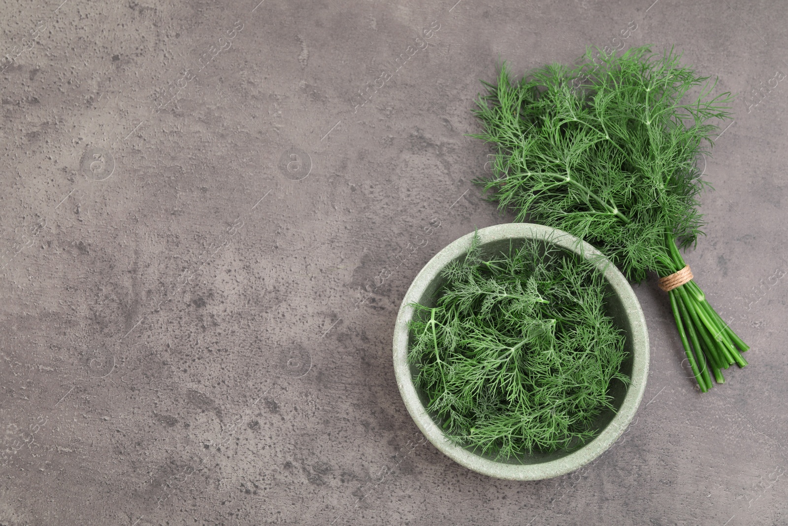 Photo of Bowl of fresh dill on grey table, flat lay. Space for text