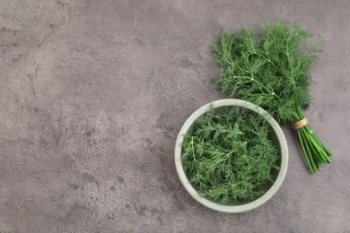 Bowl of fresh dill on grey table, flat lay. Space for text