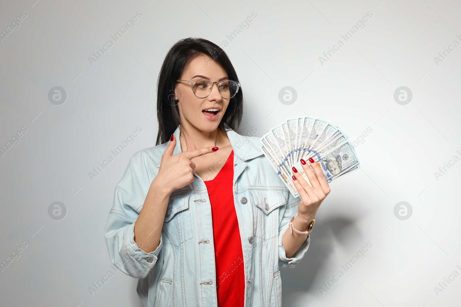 Photo of Portrait of stylish woman with money fan on light background