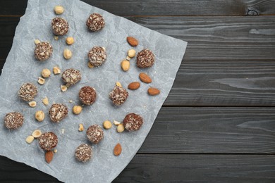 Delicious sweet chocolate candies and nuts on dark wooden table, top view. Space for text