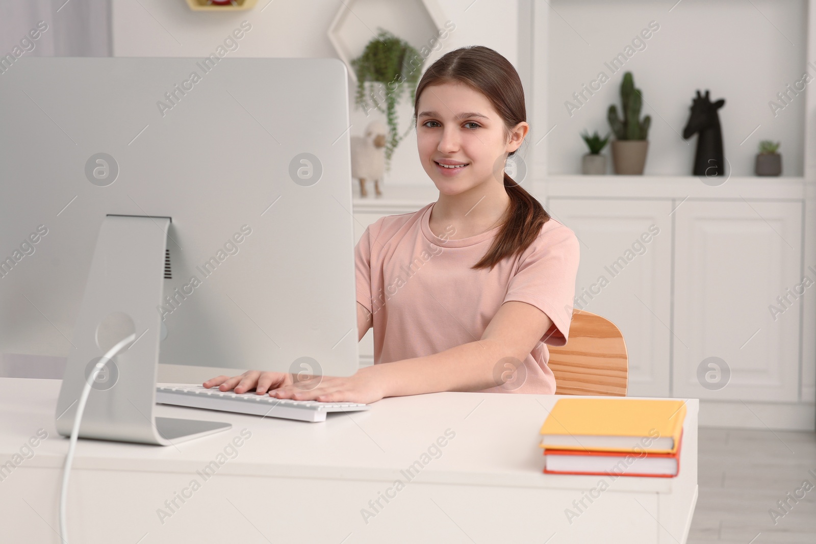 Photo of Cute girl using computer at desk in room. Home workplace