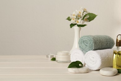 Photo of Composition with spa stones and beautiful jasmine flowers on white wooden table, space for text