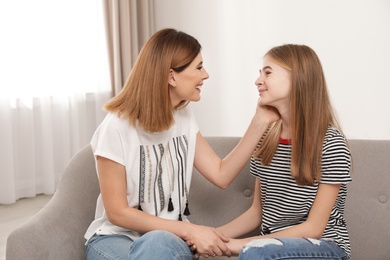 Happy mother talking with her teenager daughter at home