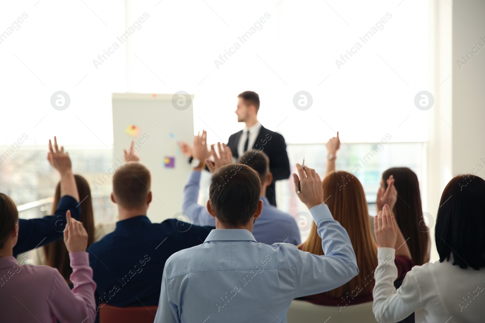 Photo of People raising hands to ask questions at business training indoors