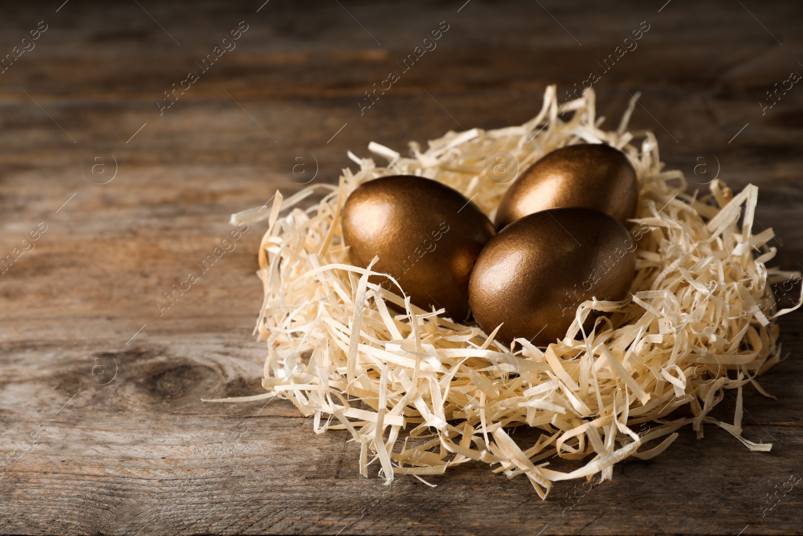 Photo of Nest with golden eggs on wooden background. Pension concept