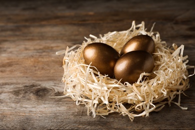 Nest with golden eggs on wooden background. Pension concept