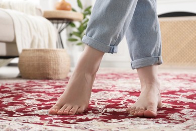 Photo of Woman standing on carpet with pattern at home, closeup