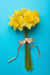 Beautiful daffodil bouquet on light blue background, top view