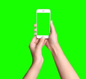 Image of Young woman holding smartphone with green screen on color background, closeup. Mockup for design