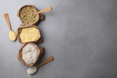 Photo of Paper bags with different types of flour on gray background