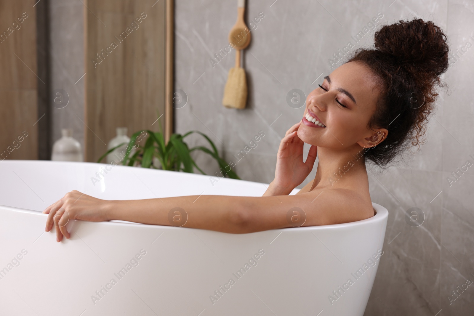 Photo of Beautiful African American woman taking bath indoors