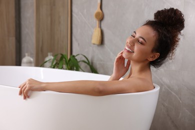 Beautiful African American woman taking bath indoors