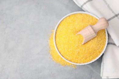 Photo of Raw cornmeal and scoop in bowl on grey table, top view. Space for text