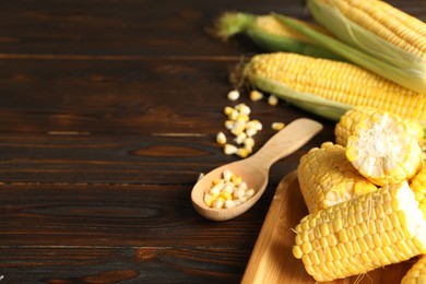 Photo of Tasty sweet corn cobs on wooden table, closeup. Space for text