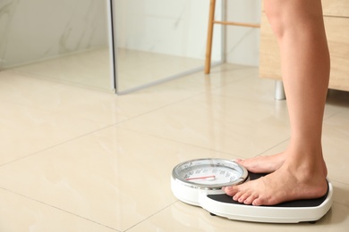 Photo of Woman standing on scales in bathroom, space for text. Overweight problem