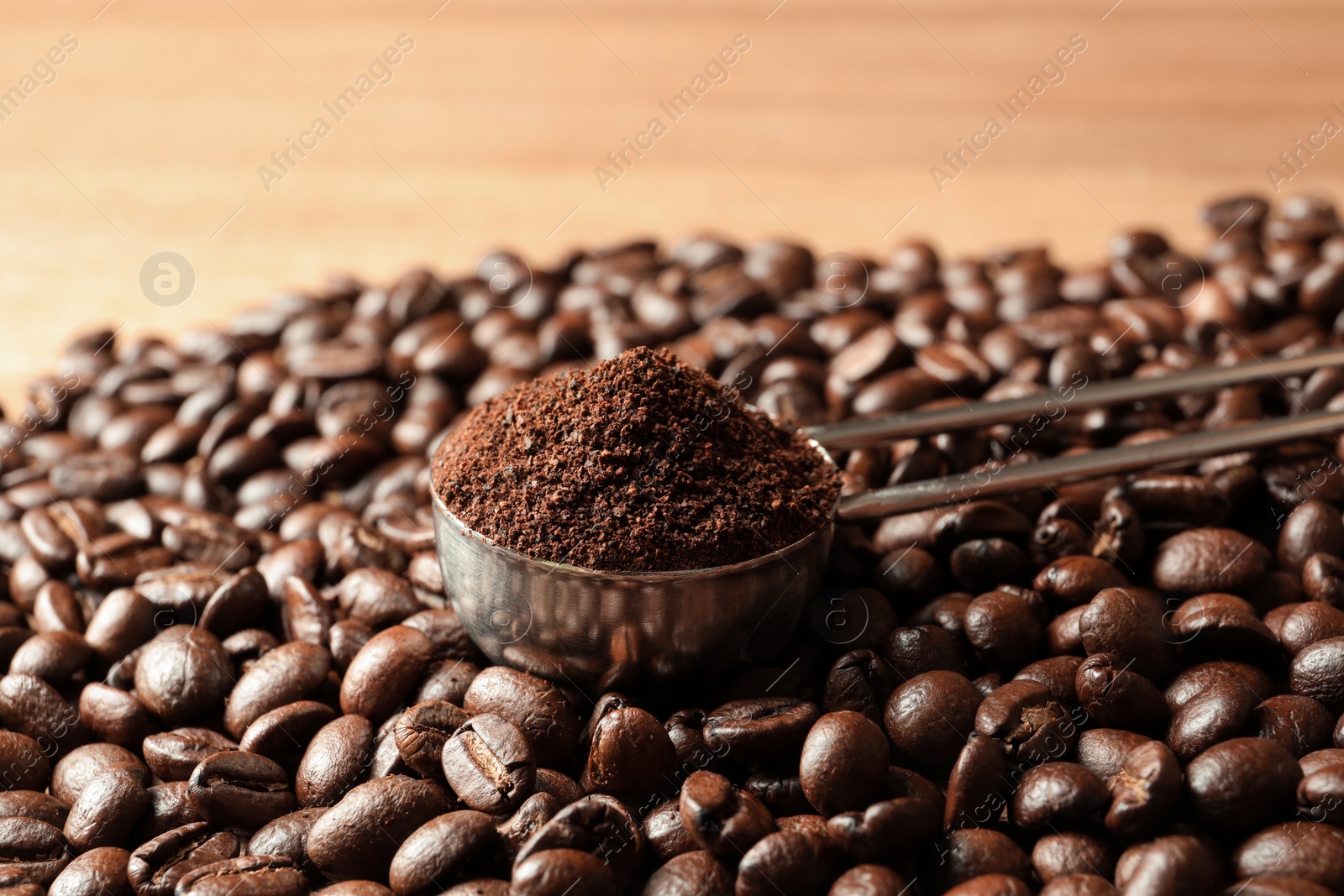 Photo of Spoon with coffee grounds and roasted beans on table, closeup