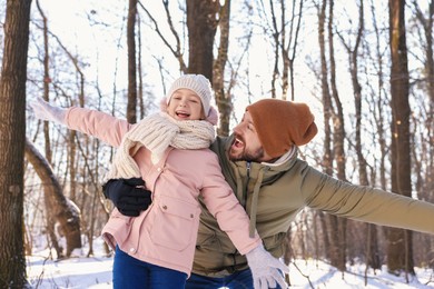 Family time. Happy father and his daughter in snowy forest