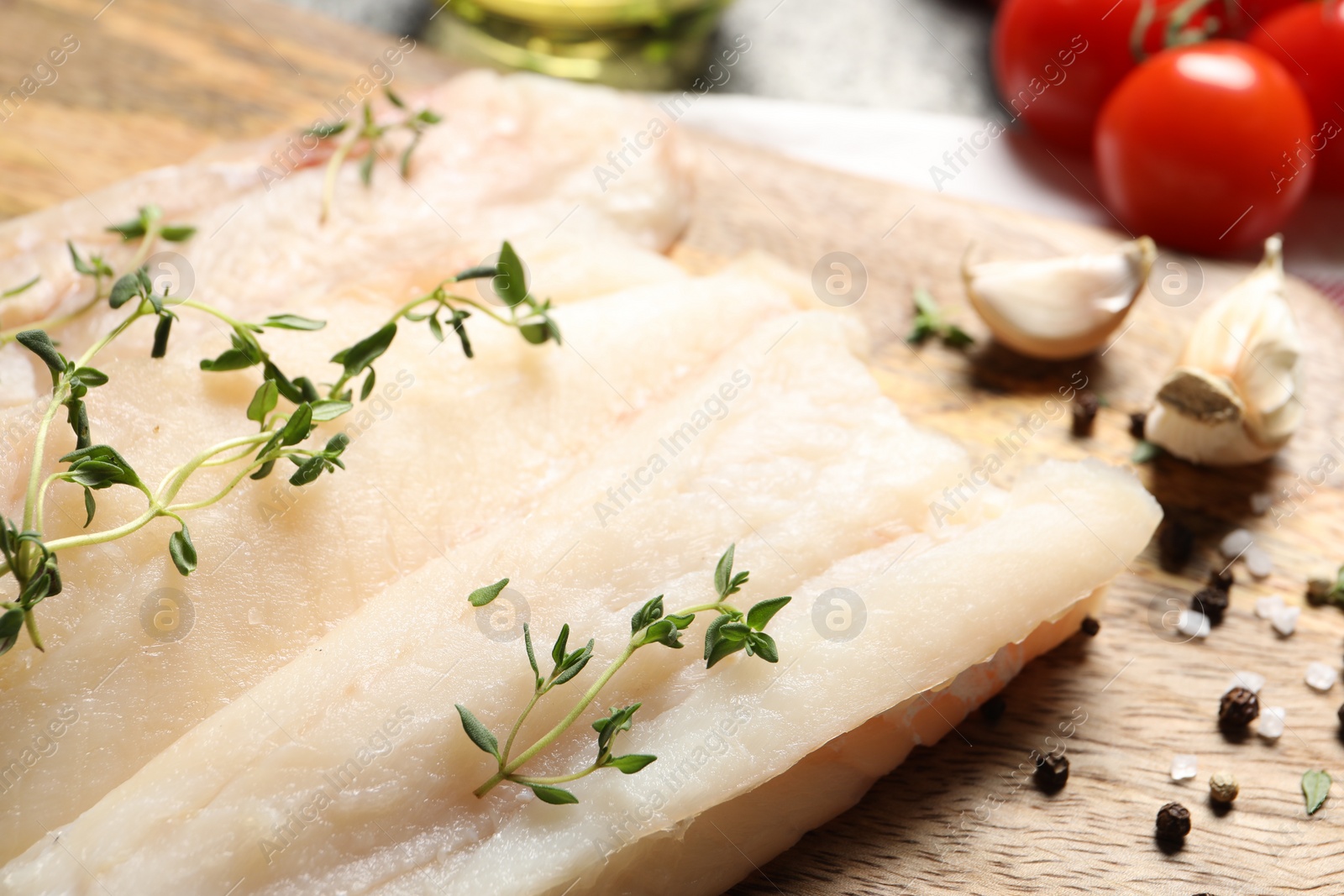 Photo of Board with raw cod fish, microgreens and spices on table, closeup