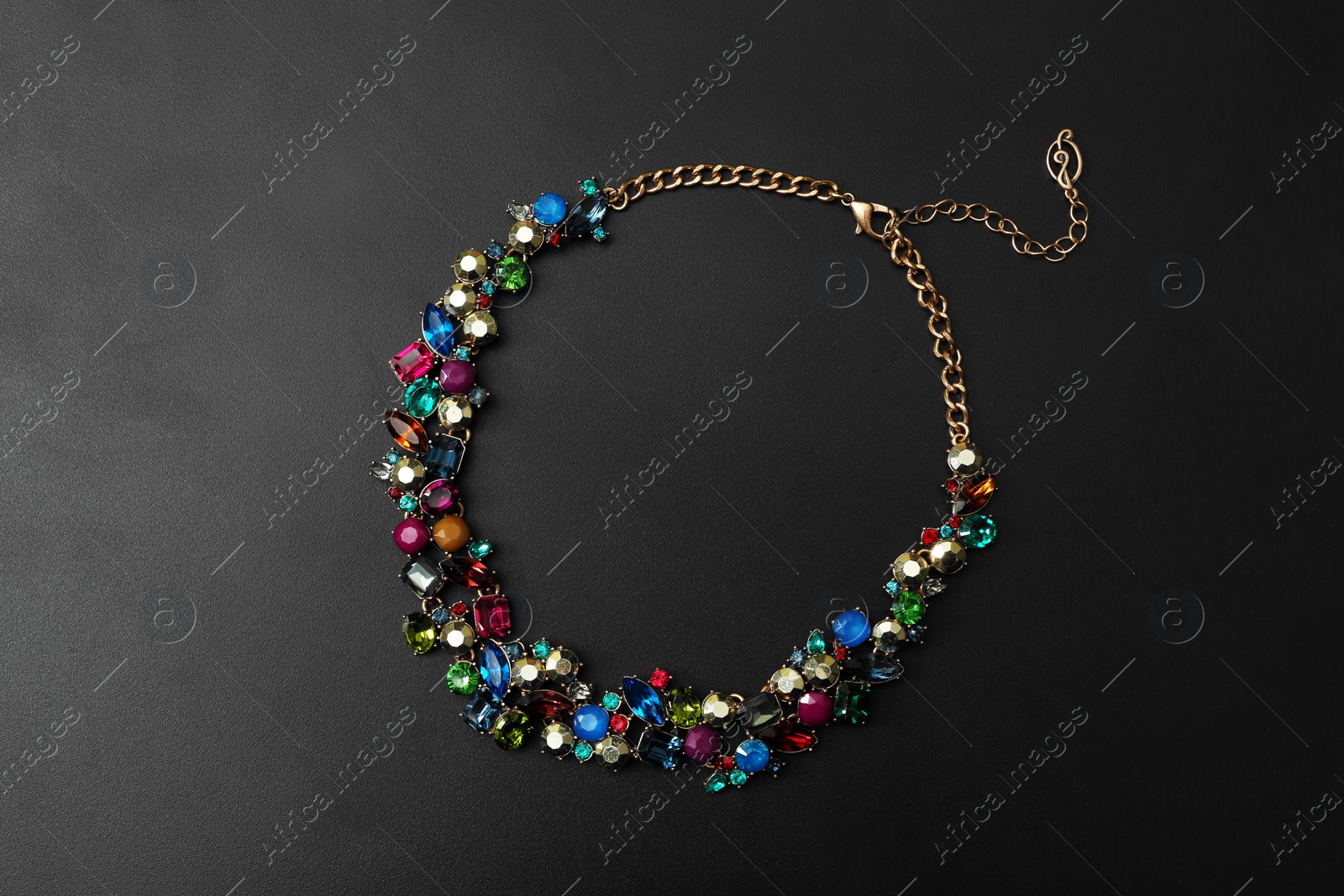 Photo of Stylish necklace with gemstones on black background, top view. Luxury jewelry