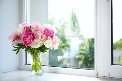 Photo of Beautiful peony bouquet in vase on windowsill indoors. Space for text