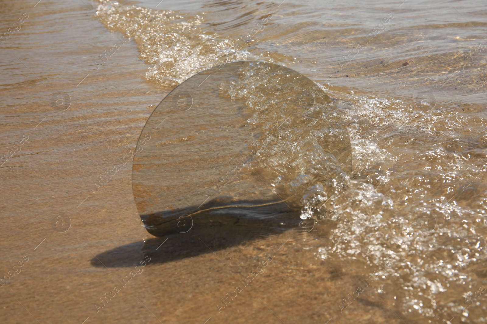 Photo of Round mirror reflecting sea on sandy beach