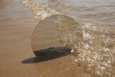 Photo of Round mirror reflecting sea on sandy beach