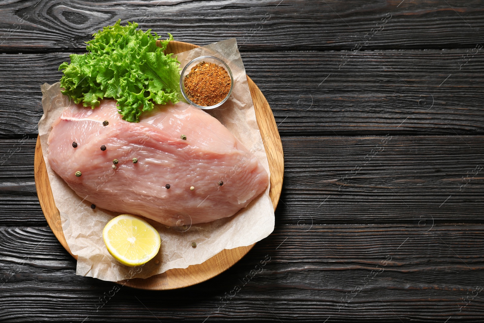 Photo of Plate with raw turkey fillet and ingredients on wooden background, top view. Space for text