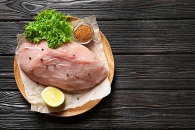 Plate with raw turkey fillet and ingredients on wooden background, top view. Space for text