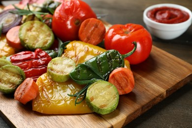 Photo of Delicious grilled vegetables with rosemary on wooden board, closeup