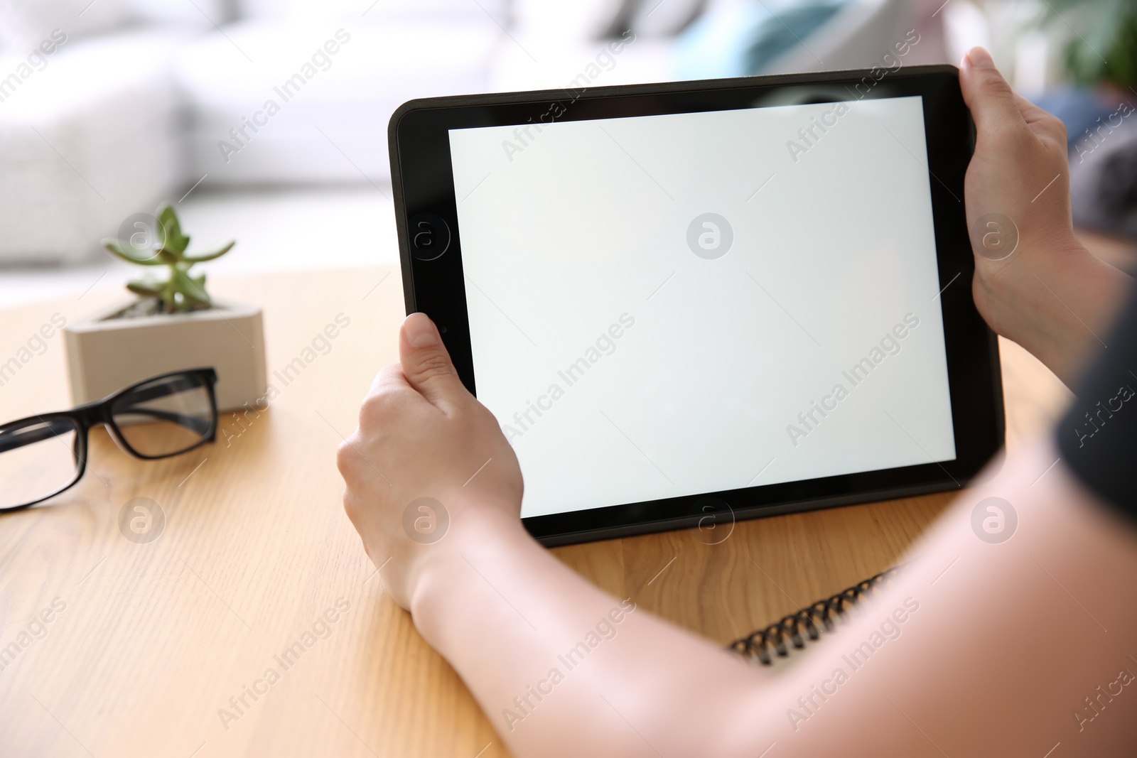 Photo of Woman working with modern tablet at wooden table, closeup. Space for design