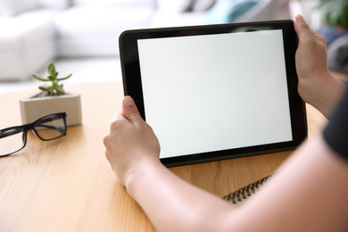 Photo of Woman working with modern tablet at wooden table, closeup. Space for design