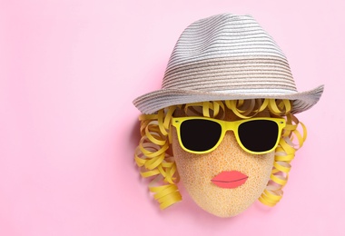 Photo of Funny face made of melon, hat and sunglasses on pink background, top view