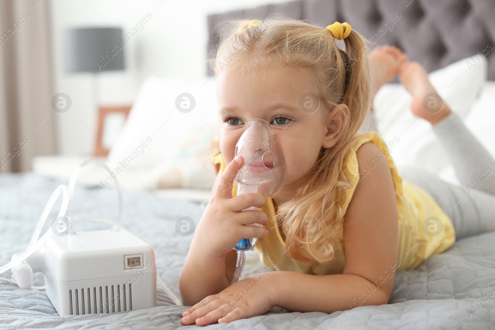 Photo of Little girl using asthma machine in bedroom. Space for text