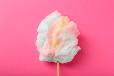 Photo of Stick with sweet cotton candy on pink background, top view