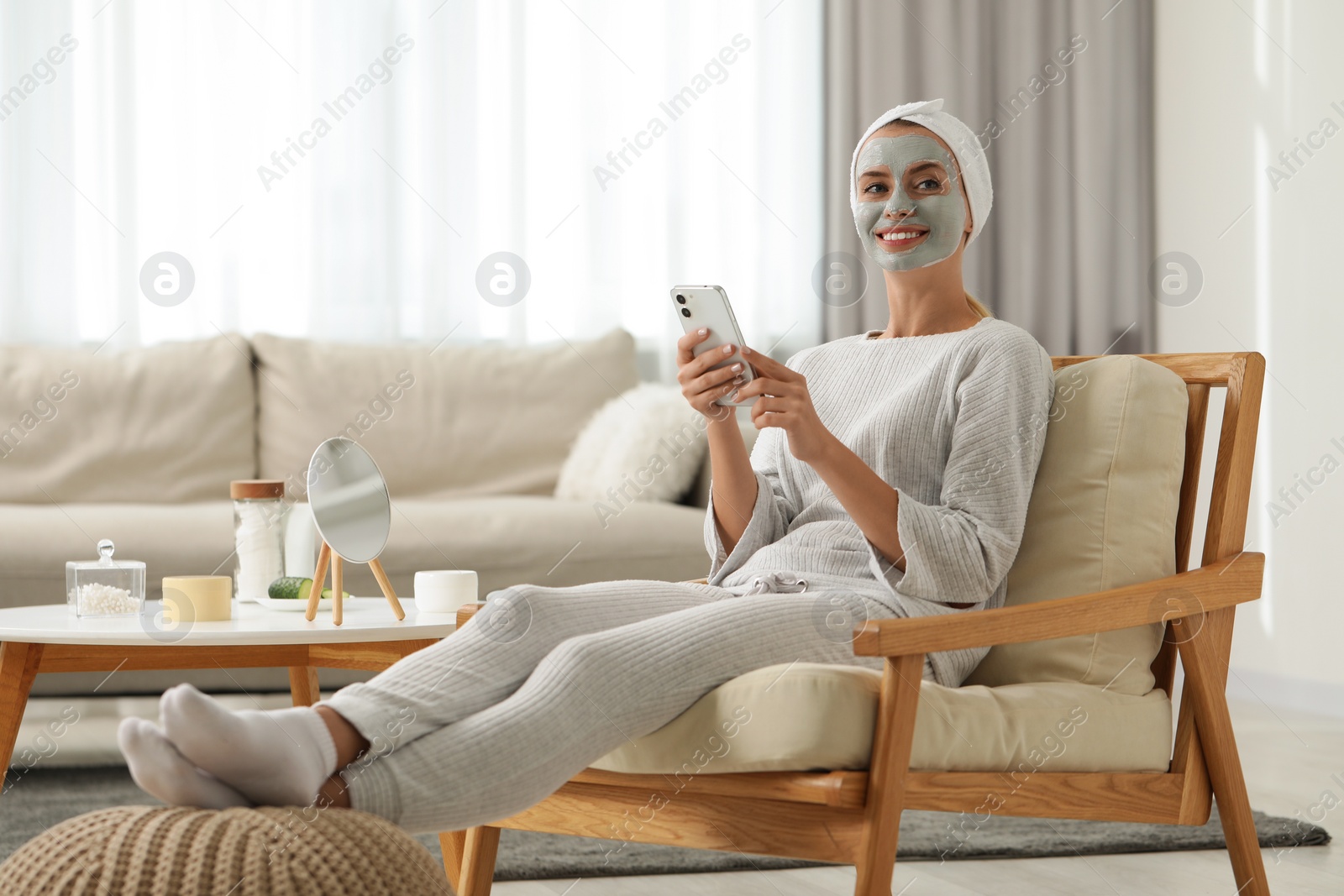 Photo of Young woman with face mask using smartphone at home. Spa treatments