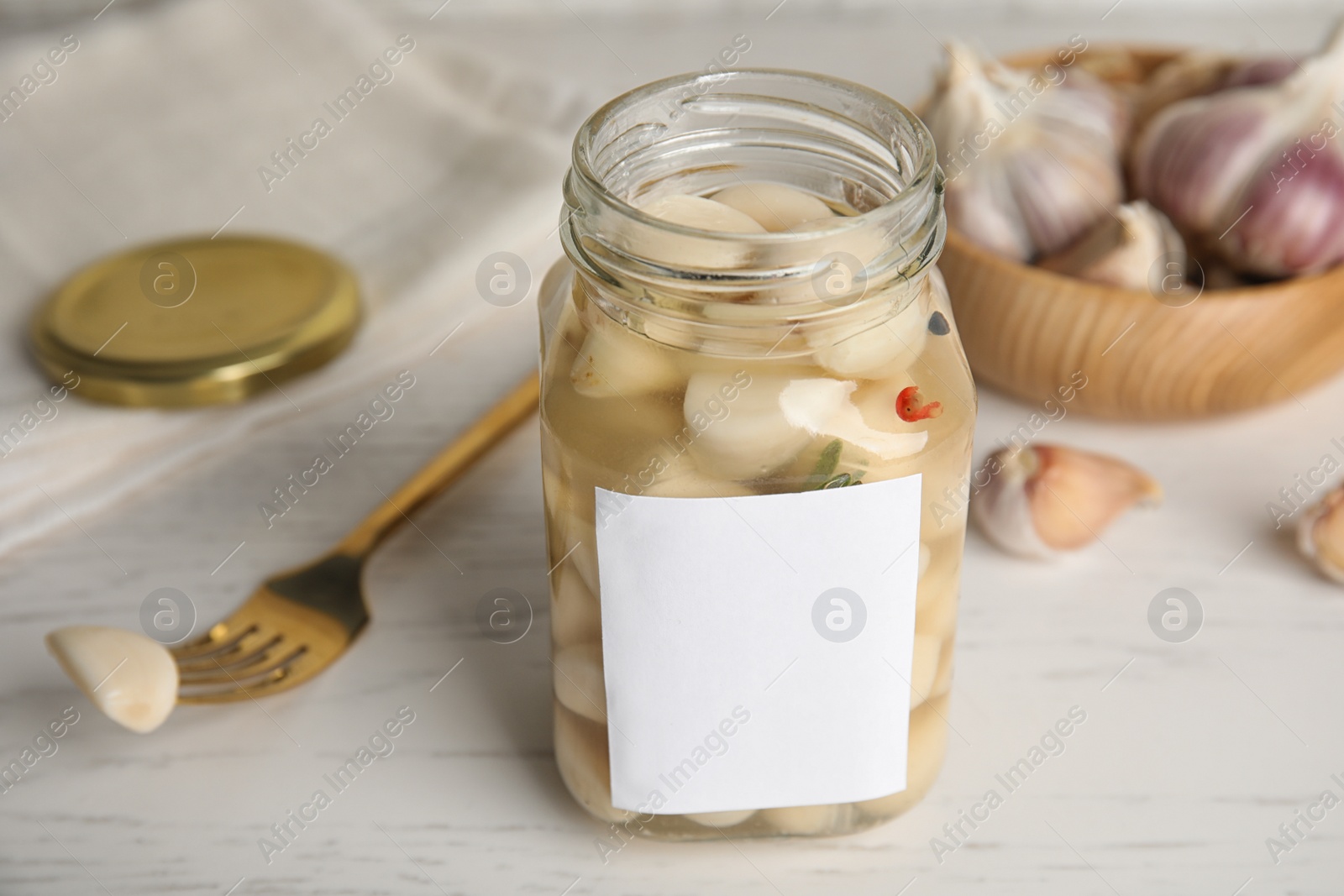 Photo of Composition with jar of pickled garlic on white wooden table