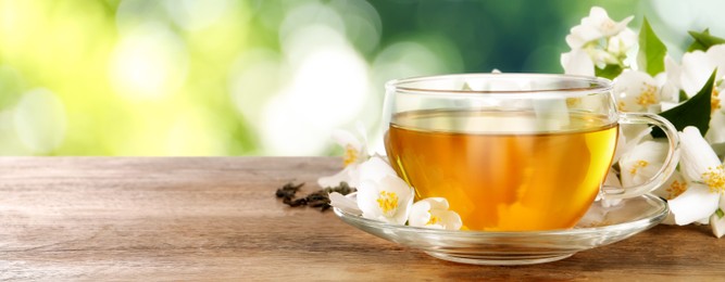 Image of Cup of jasmine tea and fresh flowers on wooden table outdoors, space for text. Banner design