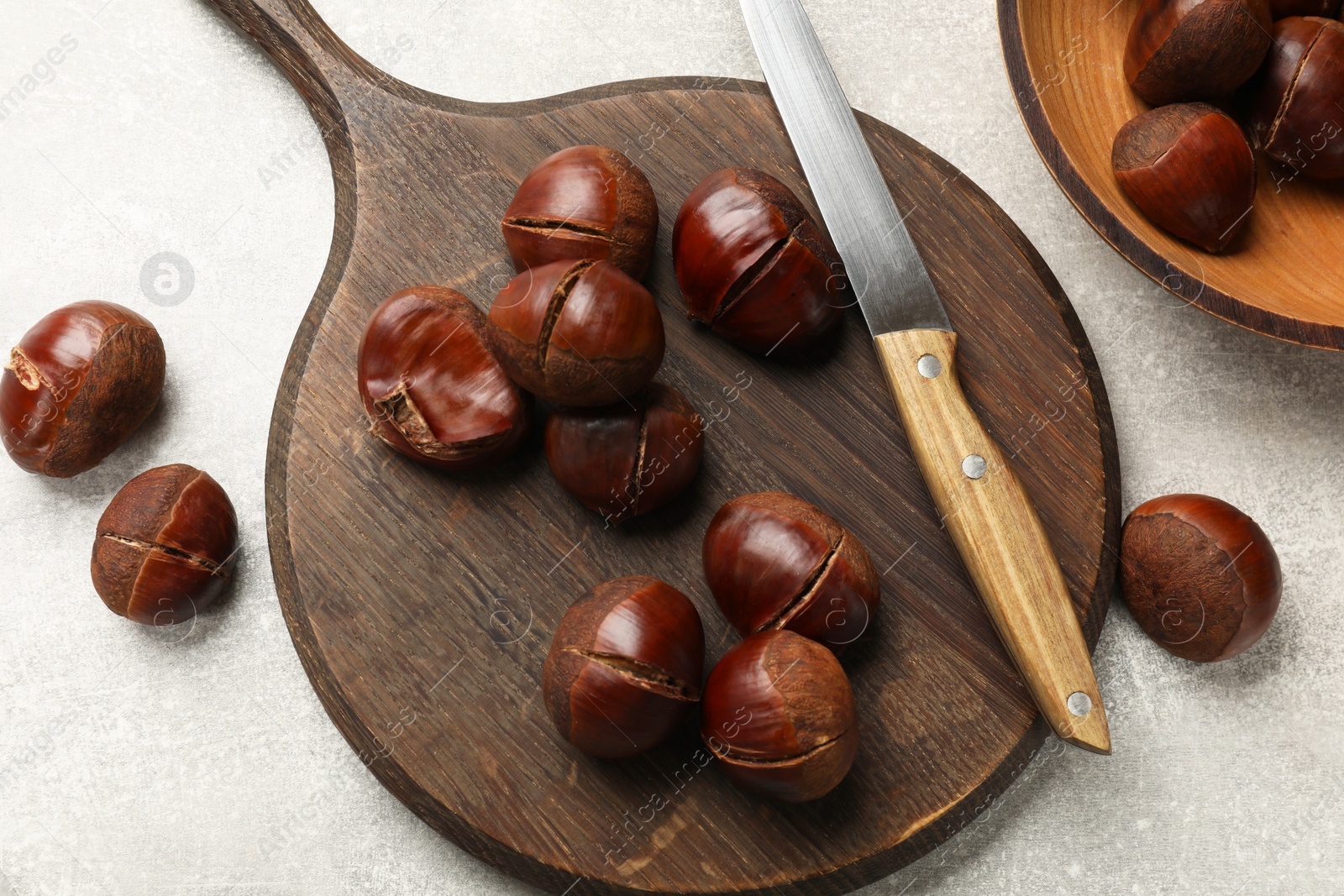 Photo of Fresh edible sweet chestnuts and knife on grey table, flat lay