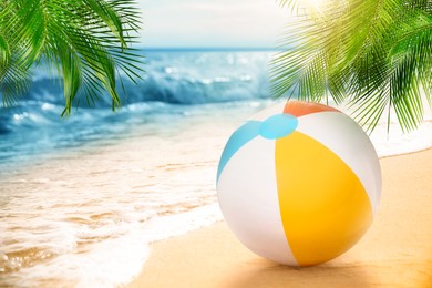 Image of Colorful beach ball on sandy coast near sea, space for text 