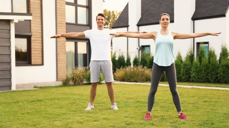 Photo of Sporty couple doing exercise on backyard. Healthy lifestyle