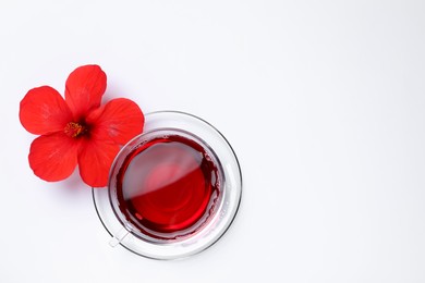 Delicious hibiscus tea and beautiful flower on white background, flat lay. Space for text