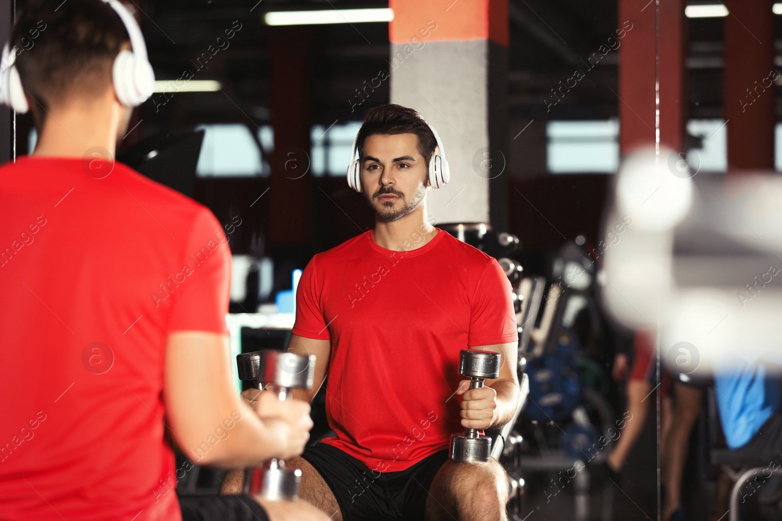 Photo of Young man with headphones listening to music and working out at gym