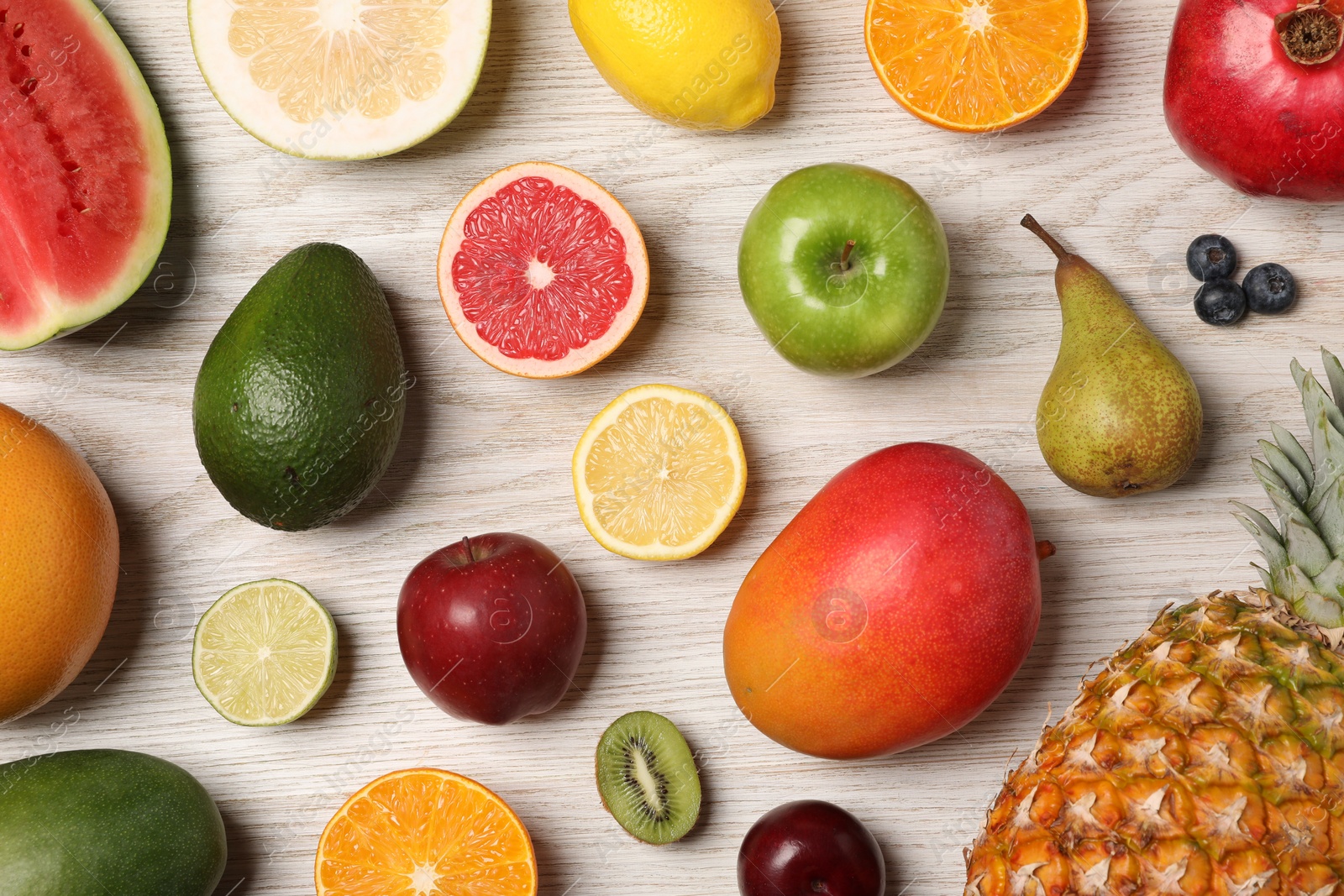 Photo of Different ripe fruits and berries on light wooden table, flat lay