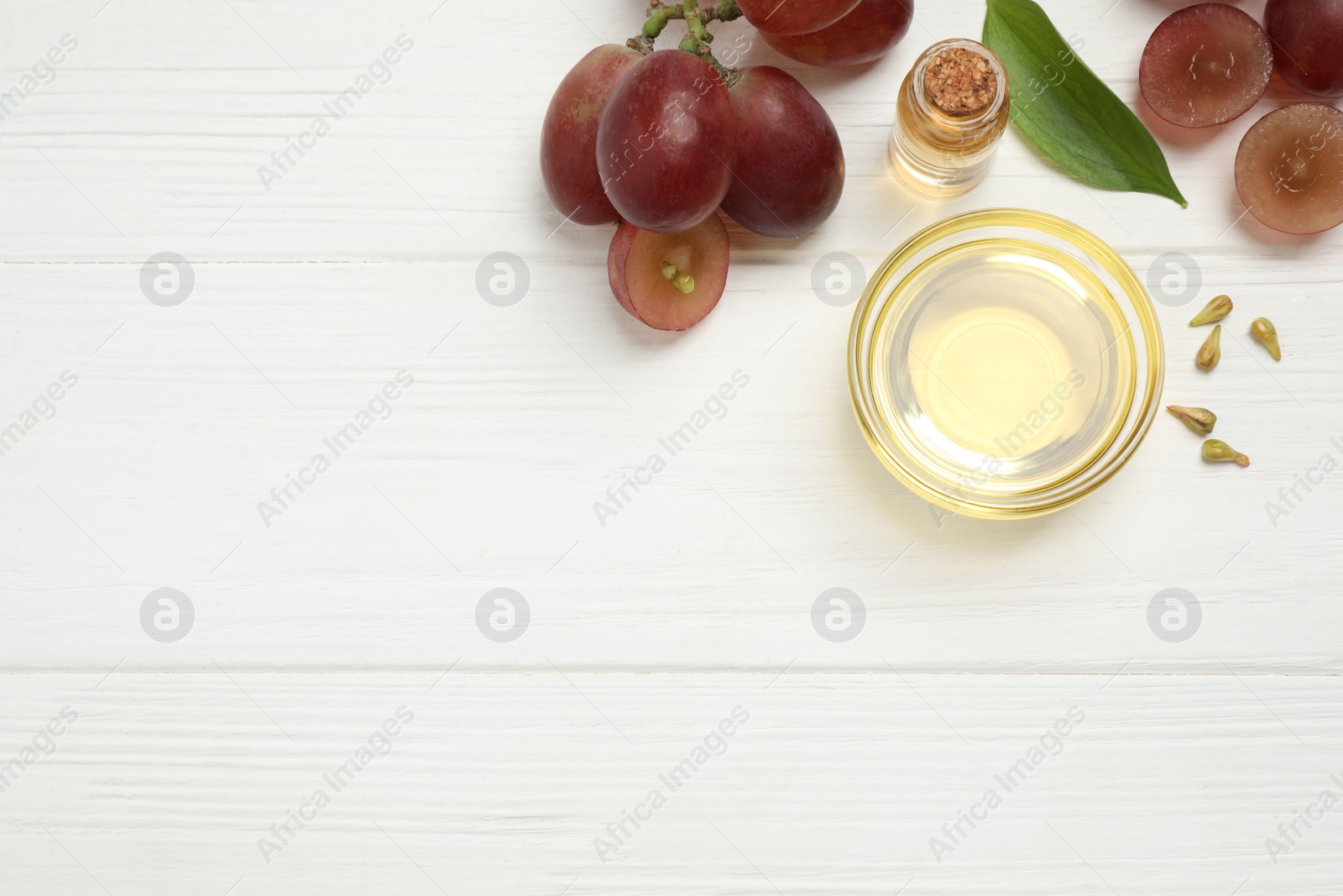 Photo of Flat lay composition with natural grape seed oil on white wooden table, space for text. Organic cosmetic