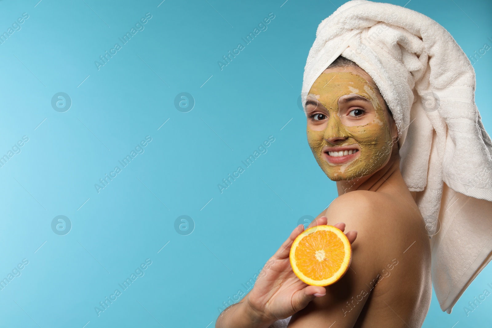 Photo of Beautiful woman with mask on face and cut orange against color background. Space for text